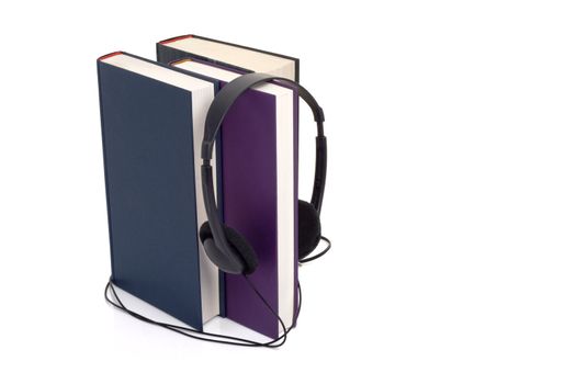 Books and headphones on white background with a faint reflection, suggesting the concept of audio books