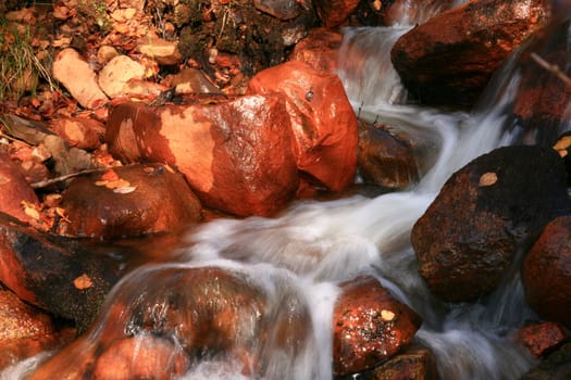 Sunlit stones in a small creek taken with a long shutterspeed.