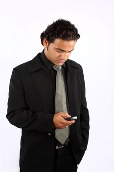 A young Indian businessman sending message on his cellphone, on white studio background.