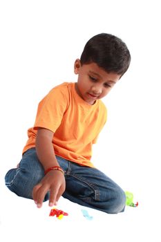 An Indian boy playing with his toys, on white studio background.
