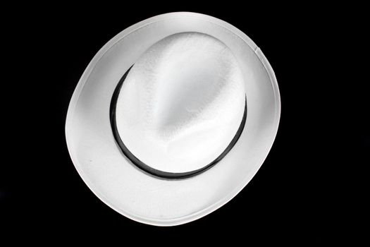 A white fedora hat of traditional Italian style, isolated on black studio background.