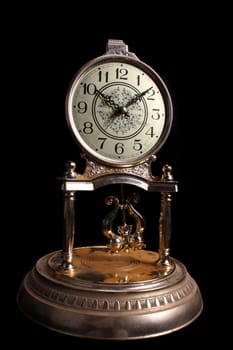 A vintage metallic clock, isolated on black studio background.