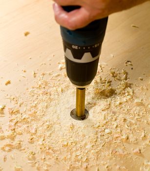 Drilling a large hole in a piece of plywood with a drill and bit
