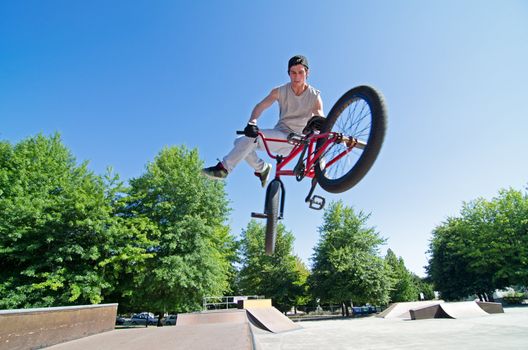 Bmx rider performing a tail whip at a quater pipe ramp on a skatepark.