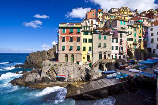 Riomaggiore fisherman village in a dramatic windy weather. Riomaggiore is one of five famous colorful villages of Cinque Terre in Italy, suspended between sea and land on sheer cliffs upon the  turquoise sea.