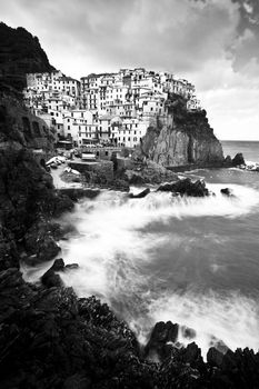 Manarola fisherman village in a dramatic windy weather in black and white. Manarola is one of five famous colorful villages of Cinque Terre (Nationa park) in Italy, suspended between sea and land on sheer cliffs upon the wild waves.