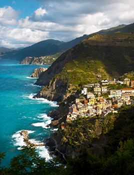 Riomaggiore fisherman village in a dramatic windy weather. Riomaggiore is one of five famous colorful villages of Cinque Terre in Italy, suspended between sea and land on sheer cliffs upon the  turquoise sea.