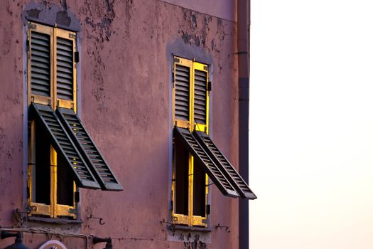 Traditional mediterranean 
vintage wooden windows glowing in the worm sunset light.
