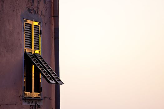 Traditional mediterranean 
vintage wooden window glowing in the worm sunset light.
