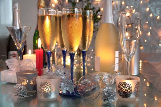 Champagne in glasses,bottles, candle lights and blurred lights on background.