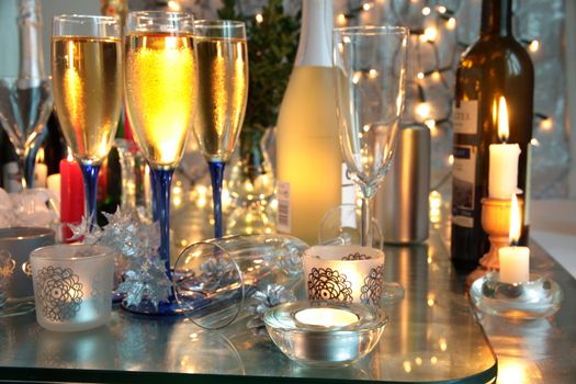 Champagne in glasses,candle lights,bottles and blurred lights on background.