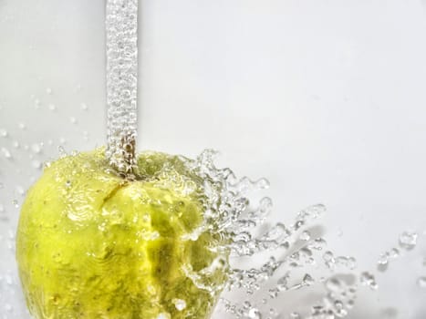 Rinsing green apple under fresh water, towards white background