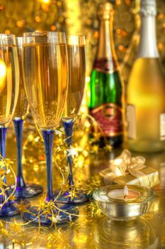 Champagne in glasses,bottles,candle light and blurred lights on gold background.