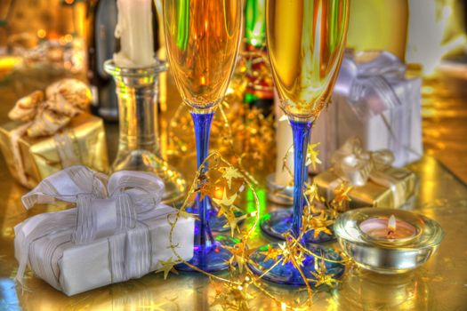 Champagne in glasses,bottles,gift boxes,candle light and blurred lights on gold background