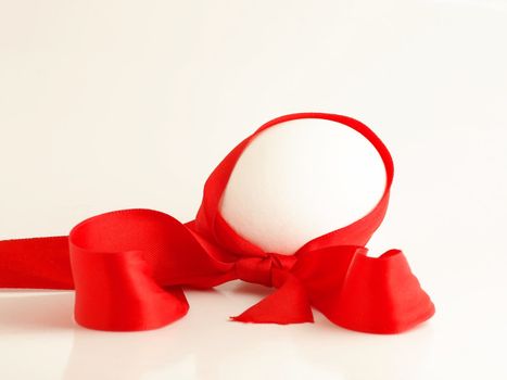 Egg on white background with a red bow wrapped around