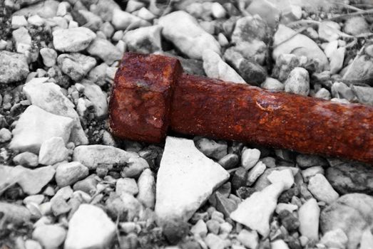 Metal nail. Reddish color of rust. On the stone base. Photographed up close. The nail is in color, everything else is black and white.