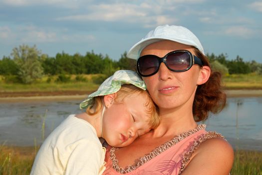 Mother and small slipping daughter outdoors in sunny summer day