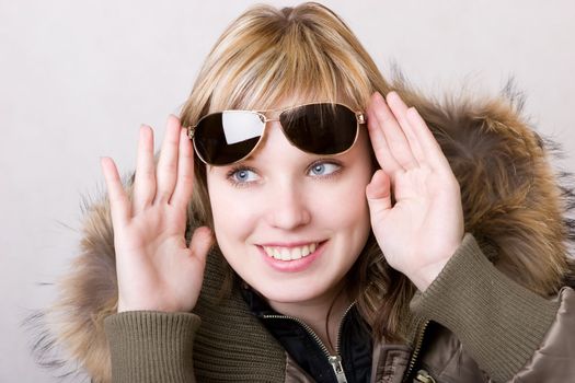 playful girl with sunglasses in a jacket with a collar of fur