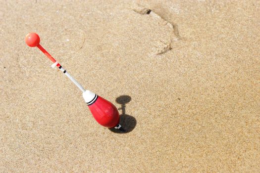 a fishing float sticked into the sand of the shore