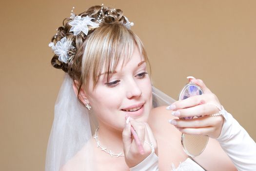 a beautiful bride carefully paints lips with a lipstick