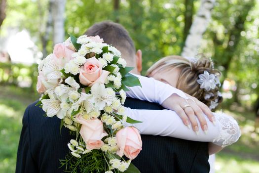 bride and groom kiss closed with a rose bouquet