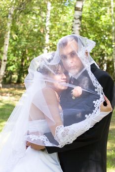 a groom and a bride are hiden in the veil