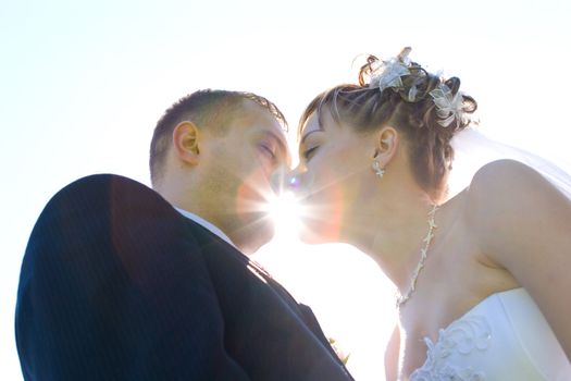 a groom and a bride kiss through the sun beams 