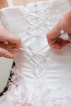 girls lace up a wedding dress of the bride