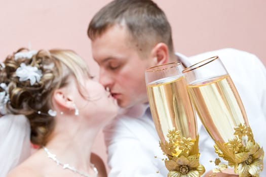 kissing Newly-married couple with full glasses of a champagne