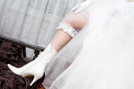 a sexy leg of the bride with garter in a white beautiful boot