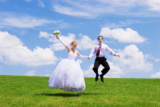 Newly-married couple on a green grass under the blue sky