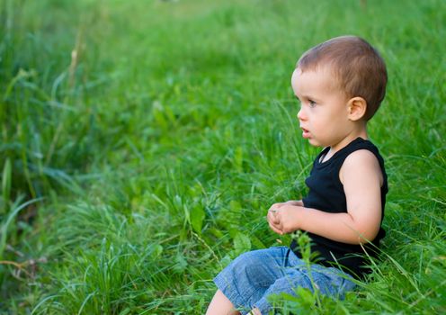 Boy sitting in a green grass