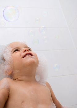 Little boy with foam on his head and bubbles