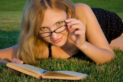 Young woman reading or studying book outdoors 