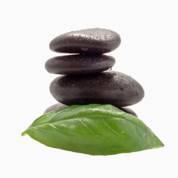 Four black stones and a green leaf over white