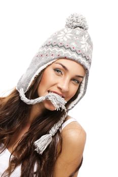 young brunette woman holding part of her winter cap with her mouth on white background