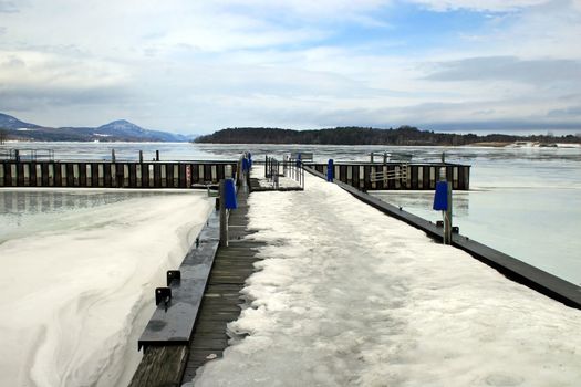 A dock and lake iced over in the winter