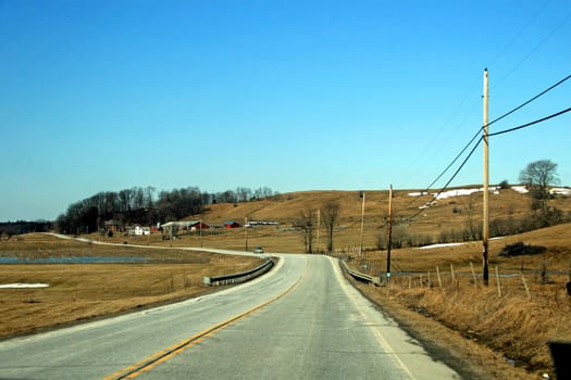 A road with brown fields in winter