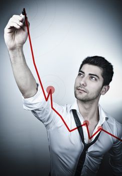 Young business man drawing a rising arrow on a glass board