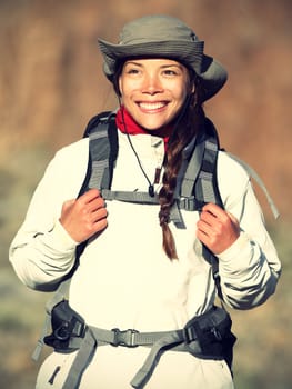 Hiker woman happy smiling outdoors while hiking in autumn or spring sporty outfit. Beautiful fresh Caucasian / Asian female model in warm evening light.