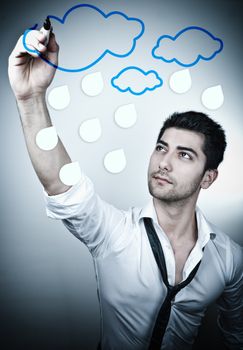 Young business man drawing rain clouds on a glass board