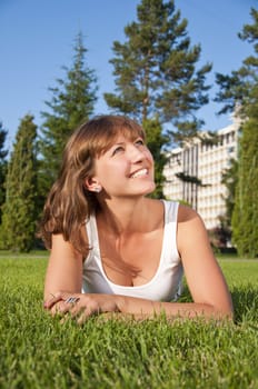 A very beautiful young woman lying down smiling in a field