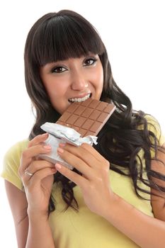 A young pretty woman biting into a block of fruit and nut fine chocolate.  White background.