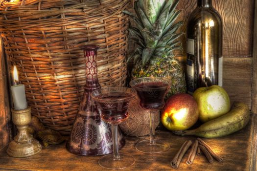 Wine in glasses,bottle,fruits,candle light,decanter,wicker basket on wooden background.
