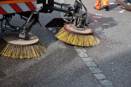 detail of a street sweeper machine/car and worker cleaning the road