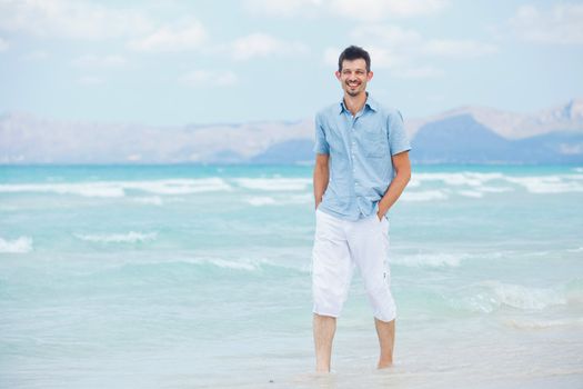 Handsome young man walking near blue sea.