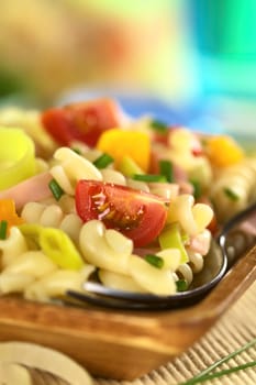 Pasta salad with leek, cherry tomato, yellow bell pepper and ham garnished with chives (Selective Focus, Focus on the tomato in the front)