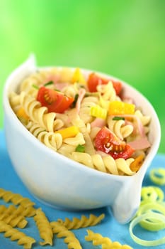 Pasta salad with leek, cherry tomato, yellow bell pepper and ham garnished with chives (Selective Focus, Focus on the tomato and the yellow bell pepper in the front)