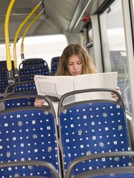 Lonley woman reading the newspaper on the bus
