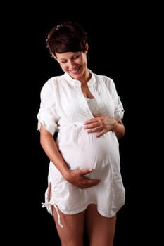 Pregnant young woman in a white shirt on the black background
